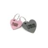Image shows 2 personalized leather pet ID tags. One is a pink heart that says "maddi" the other is a grey heart that says "london"