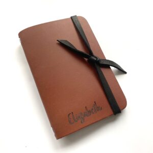 Image shows a brown leather personalized journal with the name "Elizabeth" written on it