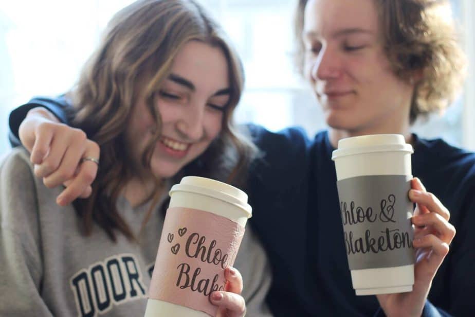 Image shows a young couple holding matching his and hers I love you coffee cups, personalized with their names and hearts on them.